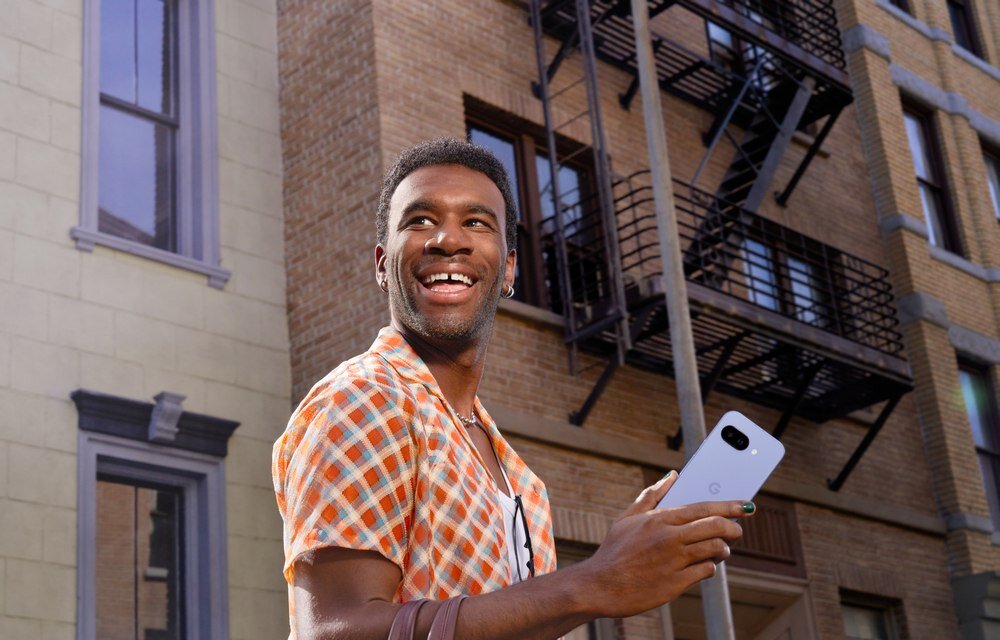 Smartfon GOOGLE Pixel 9a trzymany w ręku na tle blokowiska  