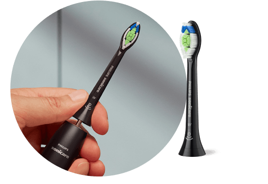 Dłoń trzymająca szczoteczkę z wyjętą końcówką. Obok znajduje się końcówka szczoteczki.