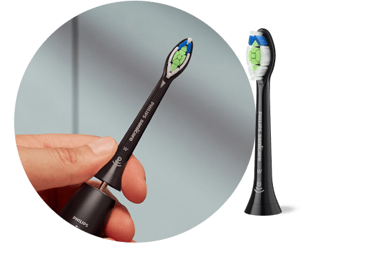 Dłoń trzymająca czarną szczoteczkę z wyjętą końcówką. Obok znajduje się końcówka szczoteczki.