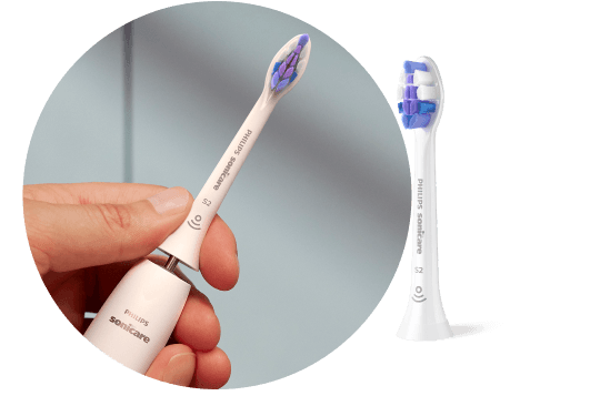 Dłoń trzymająca szczoteczkę z wyjętą końcówką. Obok znajduje się końcówka szczoteczki.