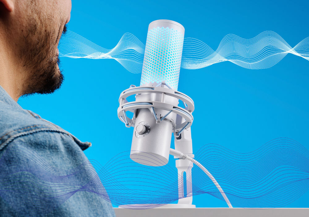 Mikrofon HYPERX QuadCast 2 Dwukierunkowy / Wielokierunkowy / Kardioidalny / Stereo Mężczyzna w dżinsowej kurtce mówi do białego mikrofonu HyperX QuadCast z mikrofonu rozchodzą się grafiki fal dźwiękowych na niebieskim tle dźwięk w wysokiej rozdzielczości uchwycenie detali profesjonalne brzmienie studyjna jakość