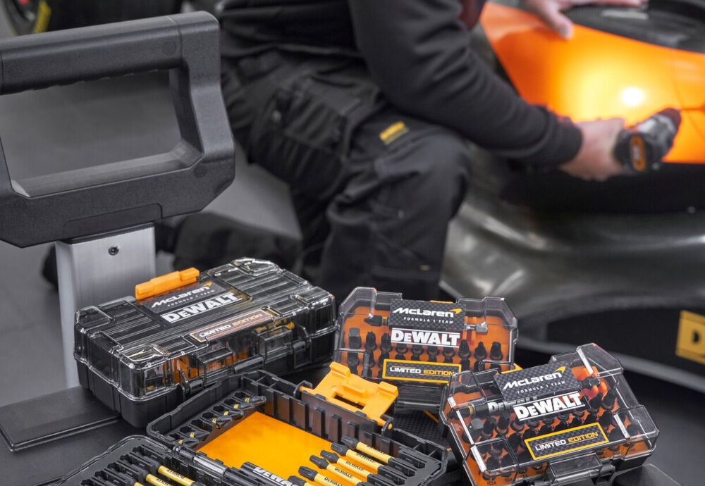 Zestaw bitów DEWALT McLaren DT70782-QZ 33 szt. pudełko z bitami na półce obok inne pudełka w tle osoba przy pracuje samochodzie precyzyjne szybkie i bezpieczne wykonanie wielu zadań przemyślana konstrukcja każdego elementu kontrola oszczędność rezultaty
