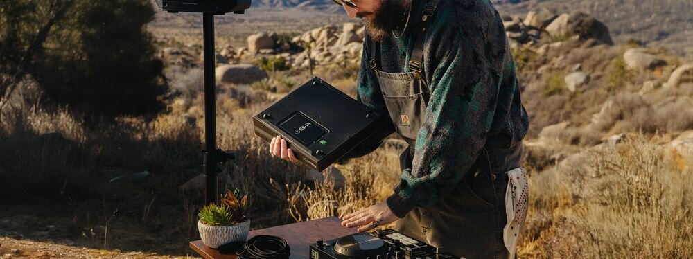 Mikser audio MACKIE ProFX10 GO bateria GB-10 do 8 godzin pracy zasilanie akumulatorowe, osoba stojąca przy stole z mikserem w ręku