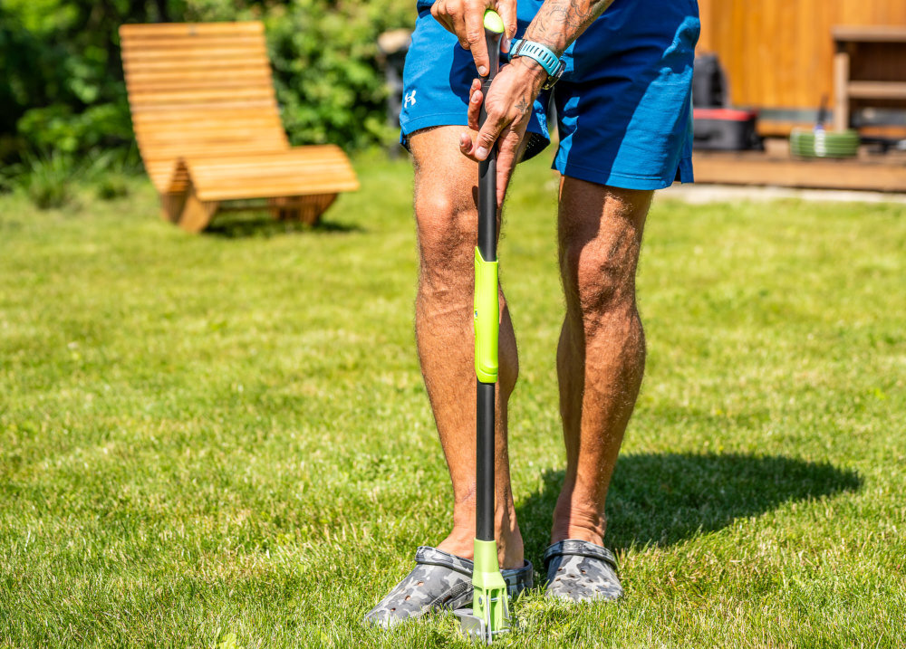 Wyrywacz do chwastów STALCO GARDEN EXP S105210372 ogród trawnik osoba wyrywa chwasty z trawnika w tle drewniany dom stabilna stopa o szerokości 31 cm ułatwia wbijanie zębów w twardą i zbitą glebę możliwość wykorzystania nacisku nogi usuwanie chwastów jest skuteczniejsze i mniej męczące