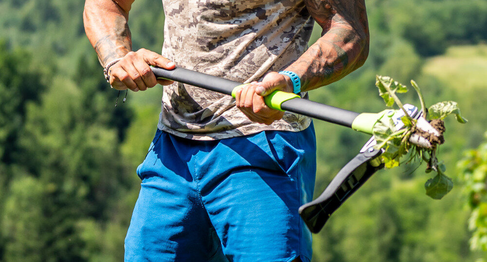 Wyrywacz do chwastów STALCO GARDEN EXP S105210372 ogród osoba trzyma wyrywacz w dłoniach rozmazane tło połączenie stali nierdzewnej, aluminium i wytrzymałego tworzywa PP odporność na wilgoć, zabrudzenia i intensywne użytkowanie ogranicza ryzyko wyginania i pękania elementów roboczych pełna funkcjonalność trwałość i stała skuteczność