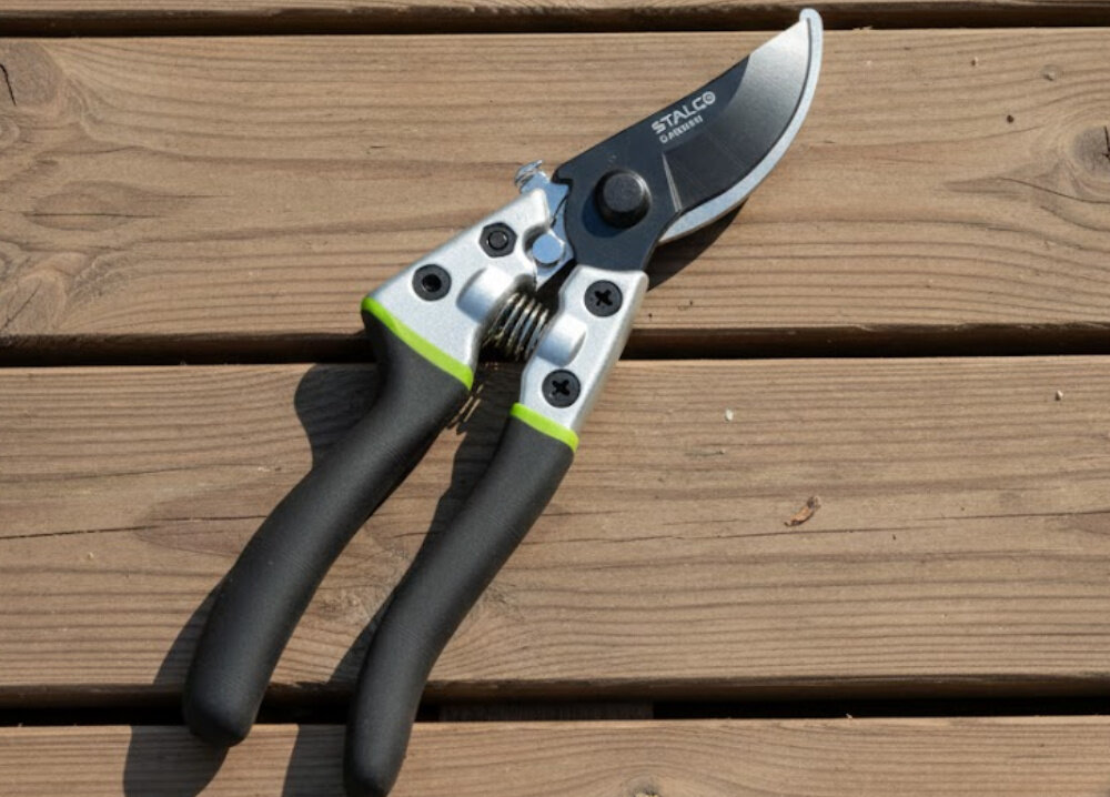 Sekator ręczny STALCO GARDEN S104010406 drewniana podłoga sekator leży na podłodze przełącznik blokady szybkie zamknięcie ostrza po zakończeniu pracy można bezpiecznie przechowywać zabezpieczenie chroni ostrze przed uszkodzeniem ogranicza ryzyko przypadkowego skaleczenia zwiększa bezpieczeństwo użytkownika