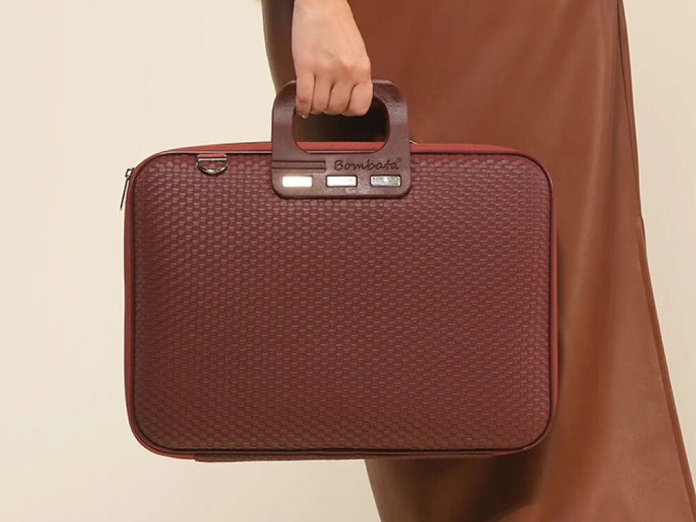 Torba na laptopa BOMBATA Trama 13-14 cali Burgundowy trzymana w ręce w tle osoba przeplatany wzór do pracy na wyjście