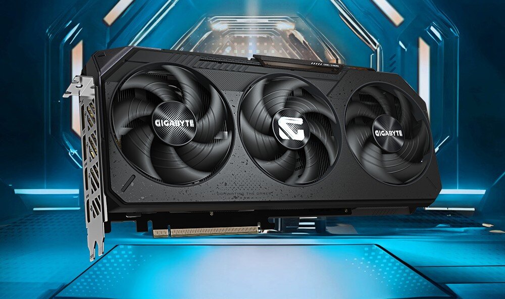 Komputer MAD DOG Powered by Gigabyte AORUS301-A11WR32WP Czarna karta graficzna z trzema wentylatorami. W tle widoczna jest futurystyczna grafika w odcieniach niebieskiego. Na karcie znajdują się logotypy producenta, karta graficzna, architektura, pamięć VRAM, chłodzenie, technologie