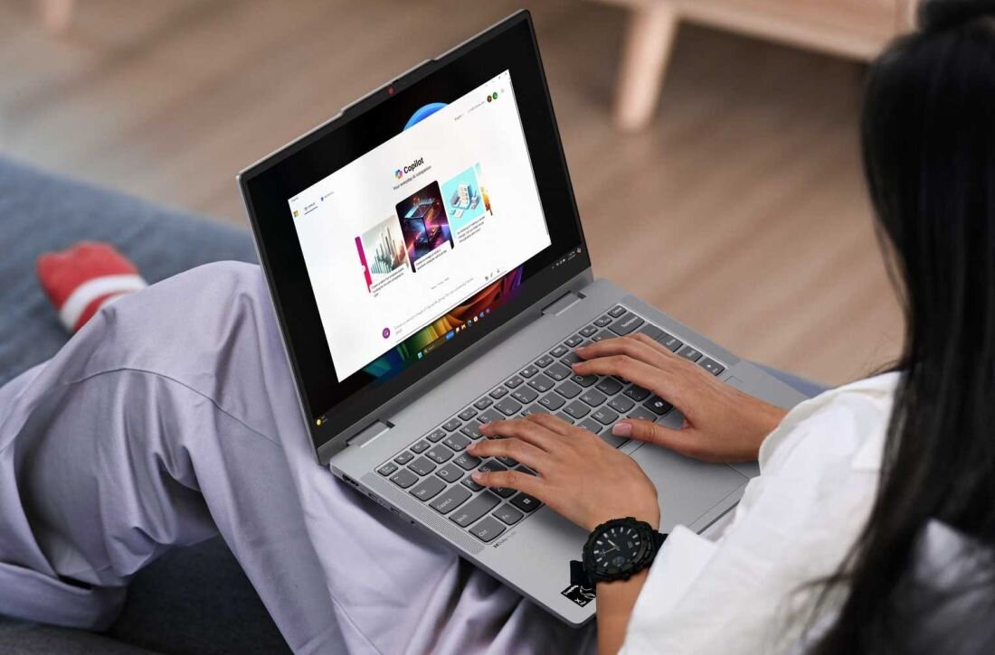 Kobieta siedzi na kanapie, korzystając z laptopa LENOVO IdeaPad 5. - Copilot+ PC