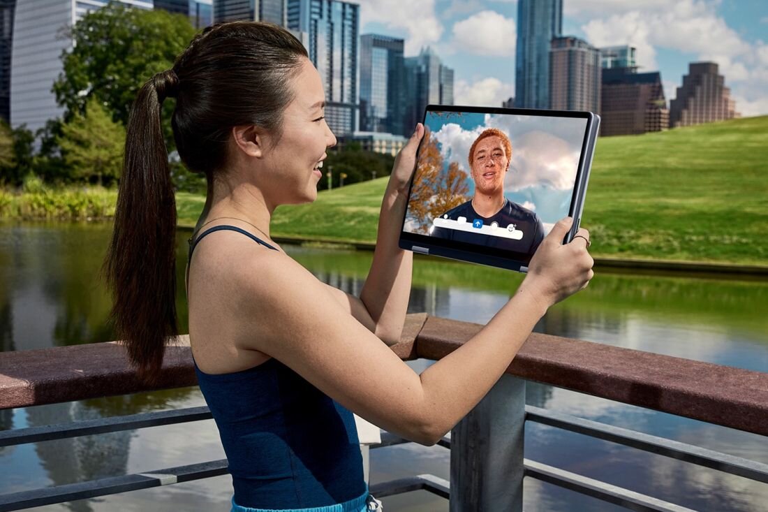 Kobieta trzyma DELL 14 Plus 2in1 z wyświetlonym zdjęciem innej osoby. - kamera FHD, dwa mikrofony oraz głośniki stereo 