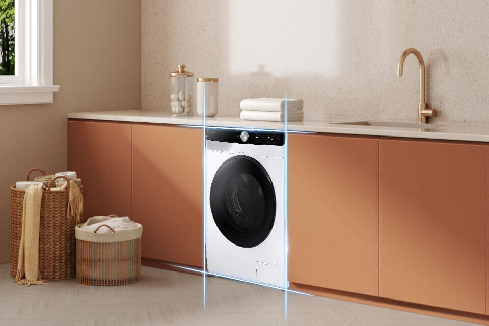 Model WD90DG6G94BKU4 – aż 9 kg prania i 6 kg suszenia w jednym urządzeniu Pralko-suszarka w zabudowie kuchennej z białym frontem i czarnym panelem sterowania. Obok znajdują się kosze na pranie oraz zlew z miedzianą baterią.