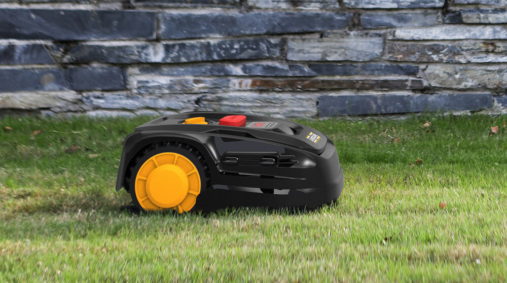 Robot koszący LANDXCAPE LX910 robot na trawie w tle kamiene ogrodzenie praca w terenie o nachyleniu do 20 stopni automatyczna obsługa wąskich przejść równomierne pokrycie całego obszaru inteligentny system nawigacji omija przeszkody i efektywnie wykorzystuje dostępną powierzchnię