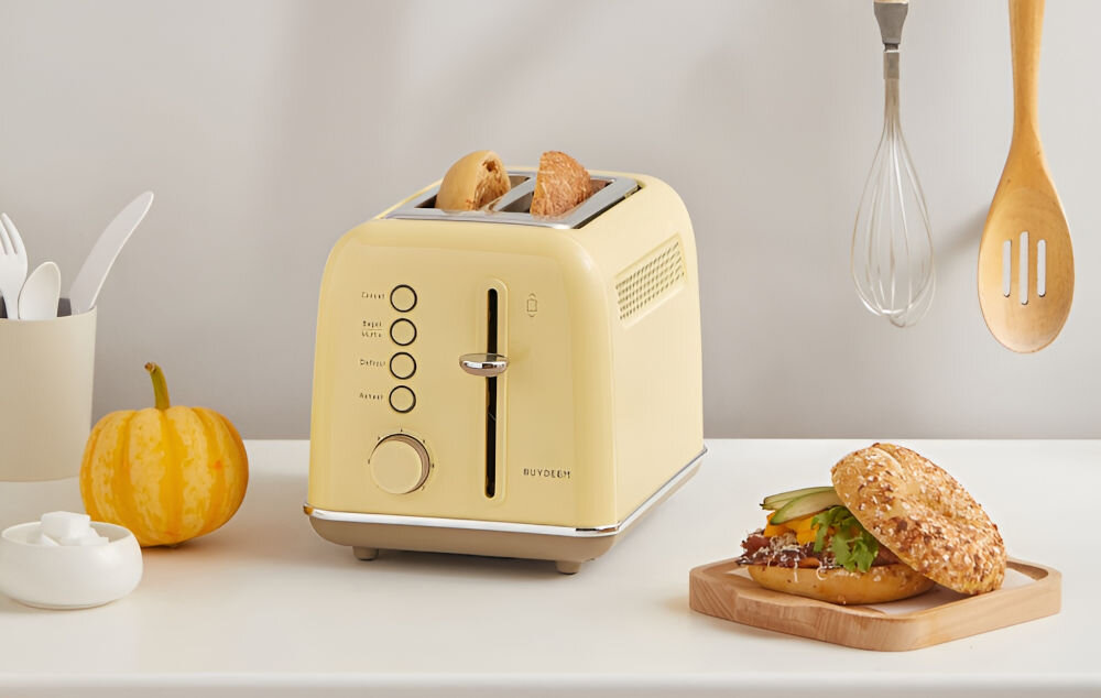 Toster BUYDEEM DT620E Żółty toster w kolorze żółtym stoi na blacie w środku znajdują sie grzanki pokrętło dźwignia przyciski chleb bajgiel grubsza kromka otwory szerokość 3,5 cm każdy rodzaj pieczywa wszechstronne urządzenie kuchenne chrupiące tosty podgrzanie kanapek odświeżenie ulubionych przekąsek dostosowanie do różnych rodzajów pieczywa optymalny efekt