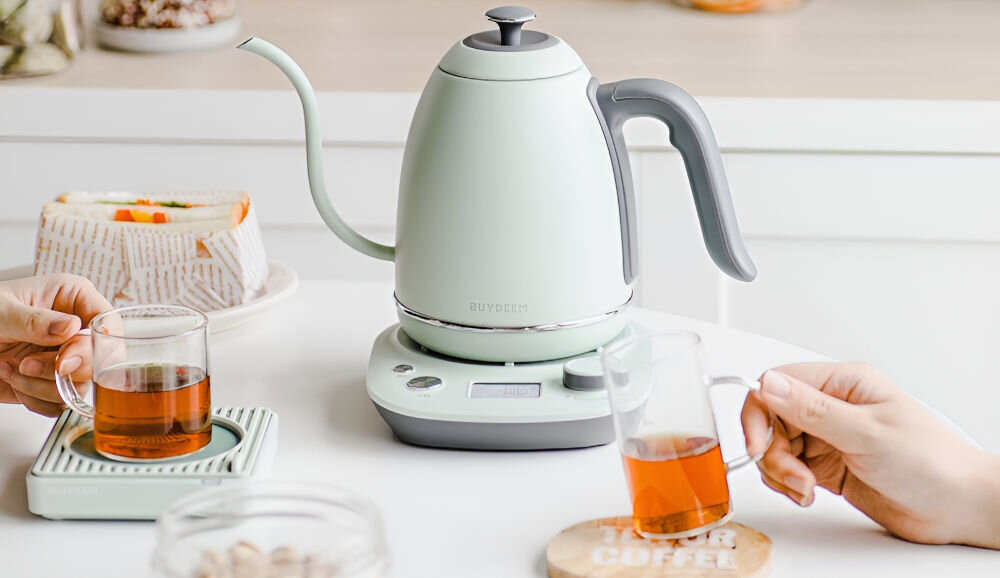 Czajnik BUYDEEM K821 Miętowy czajnik w kolorze miętowym stoi na blacie ciemna rączka podstawka pokrętło przyciski osoby pijące napój utrzymuje ciepło do 90 minut ciepła woda zawsze pod ręką do herbaty kawy innych napojów funkcja utrzymywania ciepła oszczędność czasu energii intuicyjny panel sterowania ustawienie preferowanej temperatury monitorowanie procesu gotowania na intensywne dni  