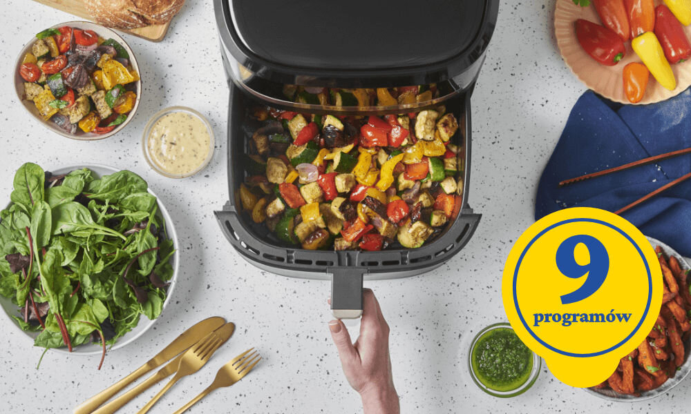 Air Fryer Frytkownica beztłuszczowa RUSSELL HOBBS Satisfry 27630-56 urządzenie stoi na blacie osoba wyciąga kosz wewnątrz upieczone danie jeden z 9 programów optymalnie przygotowany posiłek precyzyjne rezultaty pieczenie gotowanie podgrzewanie intuicyjny interfejs wszechstronność łatwe szybkie gotowanie bez stresu dla każdego entuzjasty dobrego jedzenia