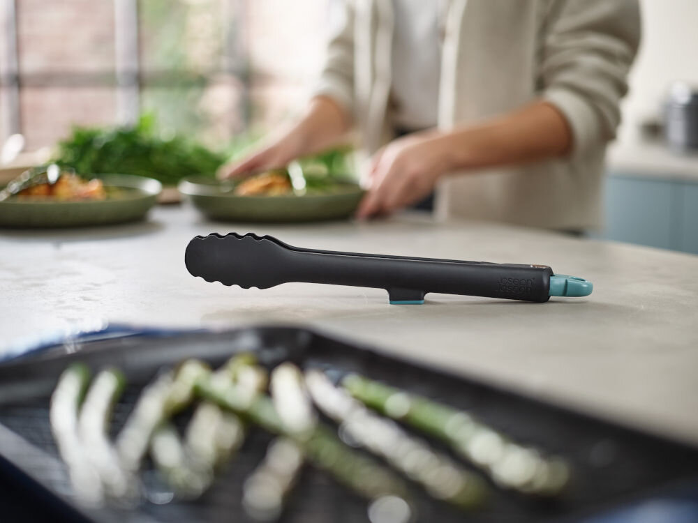 Szczypce JOSEPH JOSEPH Duo Czarno-niebieski leżące na blacie pofalowane brzegi odporność na temperatury do 200 stopni technologia elevate antypoślizgowe zakończenie podpórek