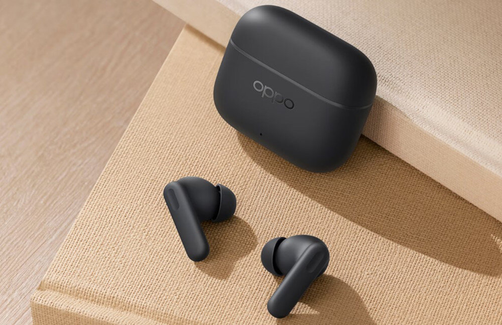 Słuchawki OPPO Enco Buds3 Pro ergonomiczne lekkie wygodne dopasowanie, słuchawki dokanałowe z etui ładującym położone na książce