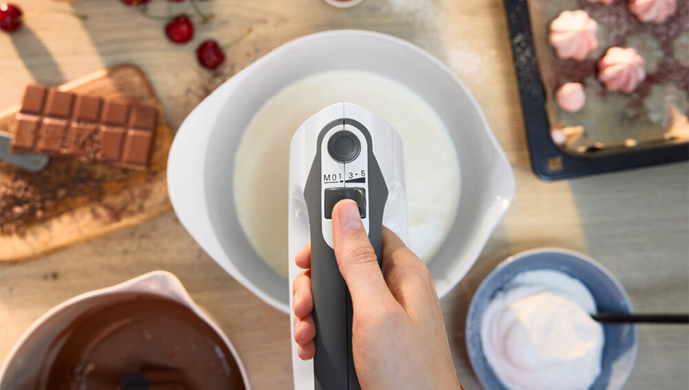 Mikser BOSCH ErgoMixx MFQ37490 Biały osoba ubija masę zbliżenie na urządzenie przycisk skala prędkości suwak pięć poziomów prędkości dostosowanie tempa pracy precyzyjne rezultaty delikatne mieszanie dynamiczne ubijanie białek jaj funkcja Turbo dodatkowa moc dokładność