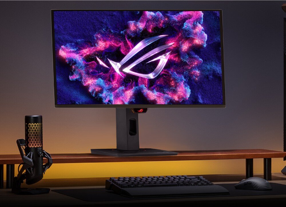 Monitor ASUS ROG Strix OLED XG27UCDMG Monitor ustawiony na drewnianej półce nad biurkiem, obok którego stoi mikrofon gamingowy, a przed nim leży klawiatura i mysz, przekątna, rozdzielczość, matryca