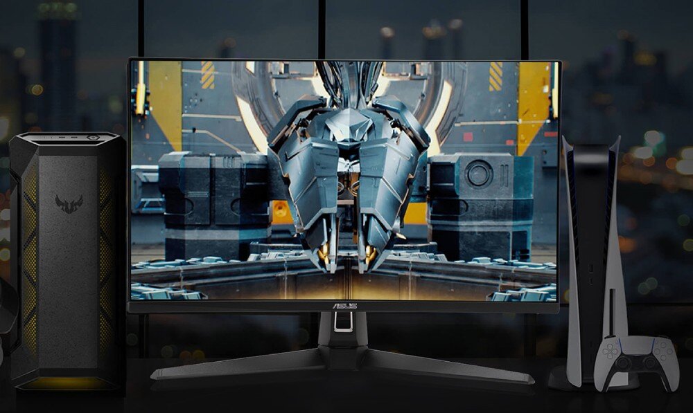 Monitor ASUS TUF Gaming VG27UQ1A Monitor stojący pomiędzy obudową komputera i konsolą do gier, wyświetlający futurystyczny statek w hangarze, ekran, przekątna, rozdzielczość, kąty widzenia
