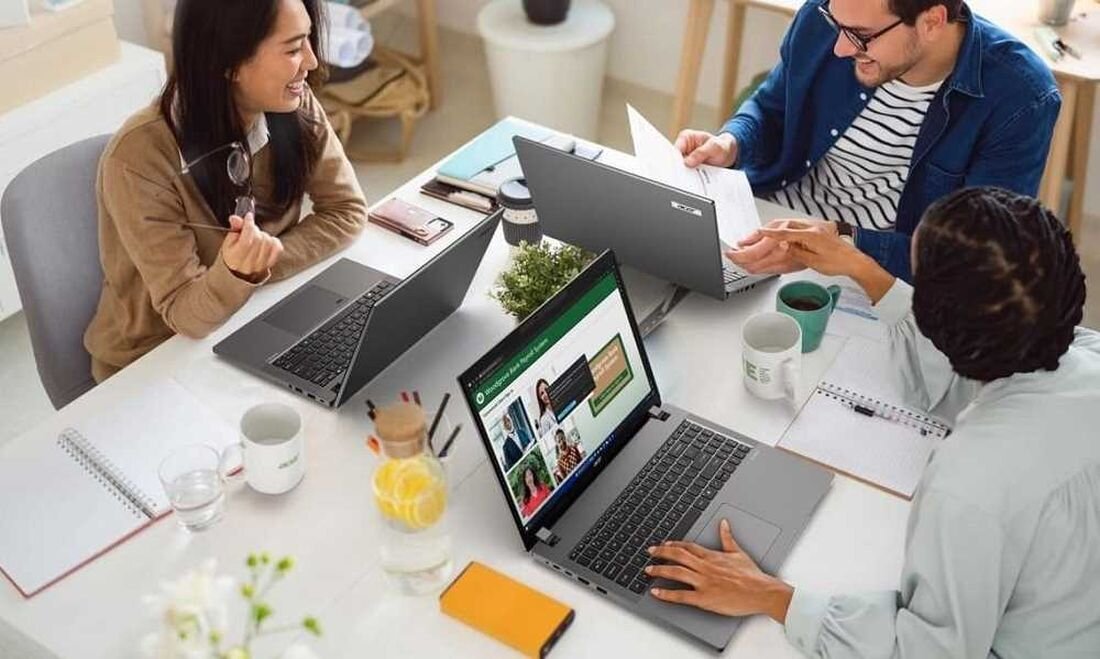 Laptop ACER TravelMate P2 - Przy stole siedzą trzy osoby z laptopami ACER TravelMate P2, zaangażowane w dyskusję i zadania.    