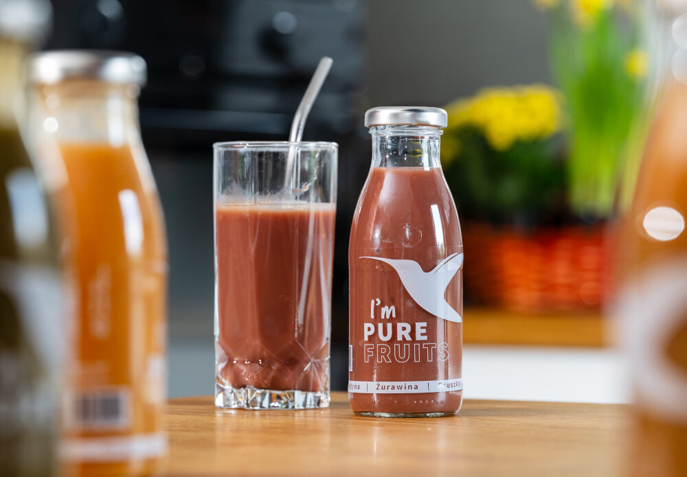 Sok COLLIBRE Pure Fruits Jeżynowo-gruszkowo-żurawinowy 15 x 250 ml butelka i szklanka wypełniona sokiem stoją na blacie z jeżyną gruszką i żurawiną naturalny smak tłoczony na zimno pasteryzowany bez użycia konserwantów bez dodatku cukru sztucznych barwników czy aromatów