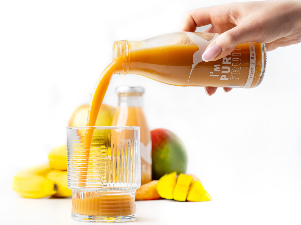 Sok COLLIBRE Pure Fruits Malinowo-porzeczkowo-borówkowy 15 x 250 ml osoba nalewa sok do szklanki w tle owoce zdjęcie na białym tle dla dzieci i dorosłych naturalność brak sztucznych składników w zestawie 15 butelek o pojemności 250 ml każda