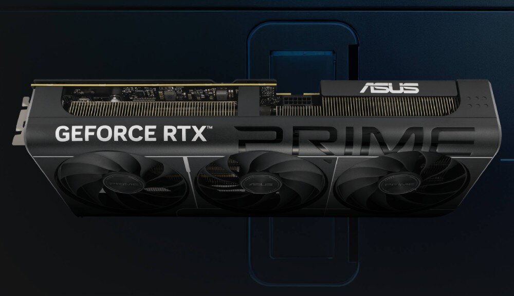 Karta graficzna ASUS Prime GeForce RTX 5070 12GB Widok z góry na kartę graficzną z wyraźnym napisem 'GEFORCE RTX' oraz 'PRIME'. W tle znajduje się fragment obudowy komputera w kolorze granatowym, konstrukcja, wielkość, format SFF-Ready