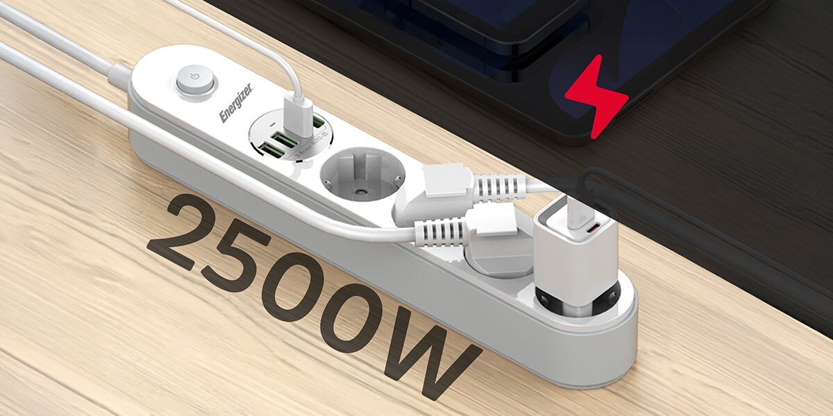 Listwa ENERGIZER EPB2500W00EU (2 m) biały Listwa zasilająca Energizer z trzema gniazdami i portami USB, z jednym kablem USB podłączonym do smartfona leżącego na biurku. W tle widać laptopa. Duży biały napis '2500W' wskazuje na maksymalne obciążenie mocy