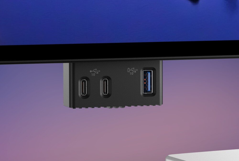 Monitor DELL UltraSharp U2725QE Zbliżenie na spód ramki monitora z wysuniętym hubem zawierającym dwa porty USB-C oraz jeden port USB-A, na fioletowym tle, porty, złącza, wyjscia wideo