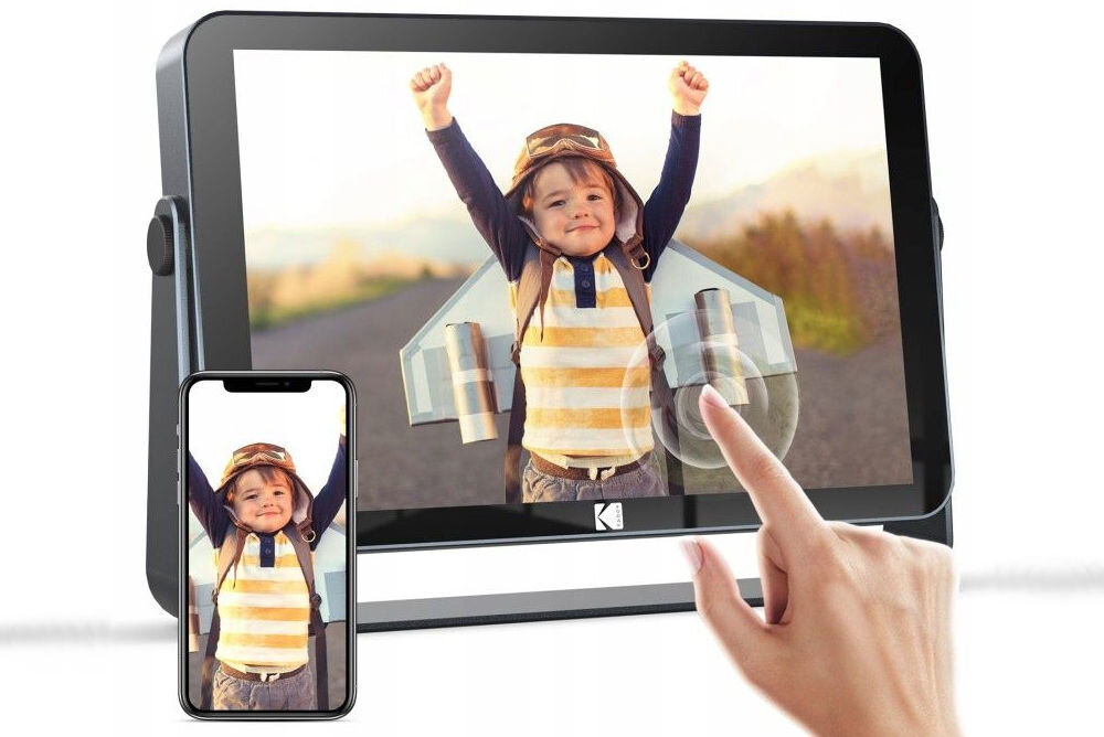 Ramka cyfrowa KODAK SB9782 Czarny prezentacja ramki ze zdjęciem na białym tle obok telefon i ręka dotykająca ramki automatyczny pokaz slajdów efekty interwały obsługa muzyki filmów formaty centrum rozrywki