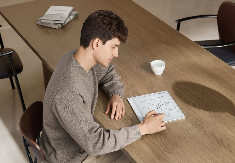 Czytnik e-booków ONYX Boox Note Max 13.3 cala, Wi-Fi Szary prezentacja urządzenia podczas korzystania przez chłopaka urządzenie leżące na stole E Ink Carta 1300 rozdzielczość wyraźny obraz naturalne wrażenie pisania BOOX Super Refresh redukcja opóźnienia brak podświetlenia ograniczenie zmęczenia wzroku