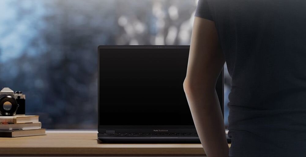 Osoba stoi przed laptopem ASUS VivoBook z funkcją Adaptive Lock przy biurku w domowym środowisku pracy 