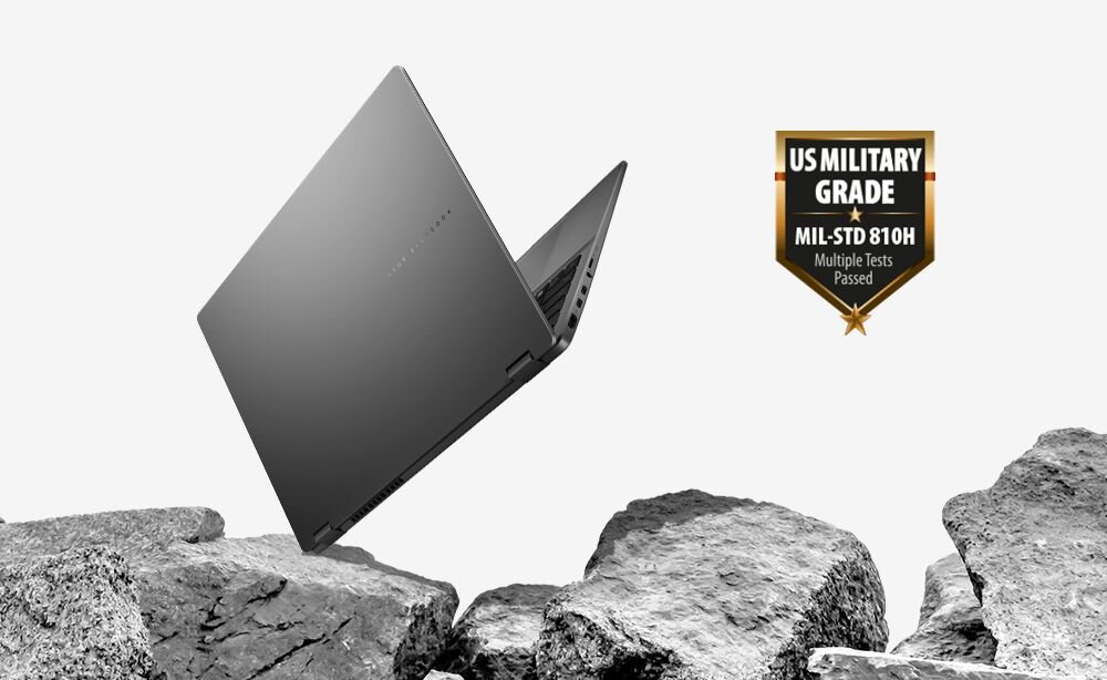 Laptop ASUS VivoBook z certyfikatem MIL-STD-810H unosi się nad kamieniami, prezentując wytrzymałą obudowę w trudnym środowisku użytkowania 