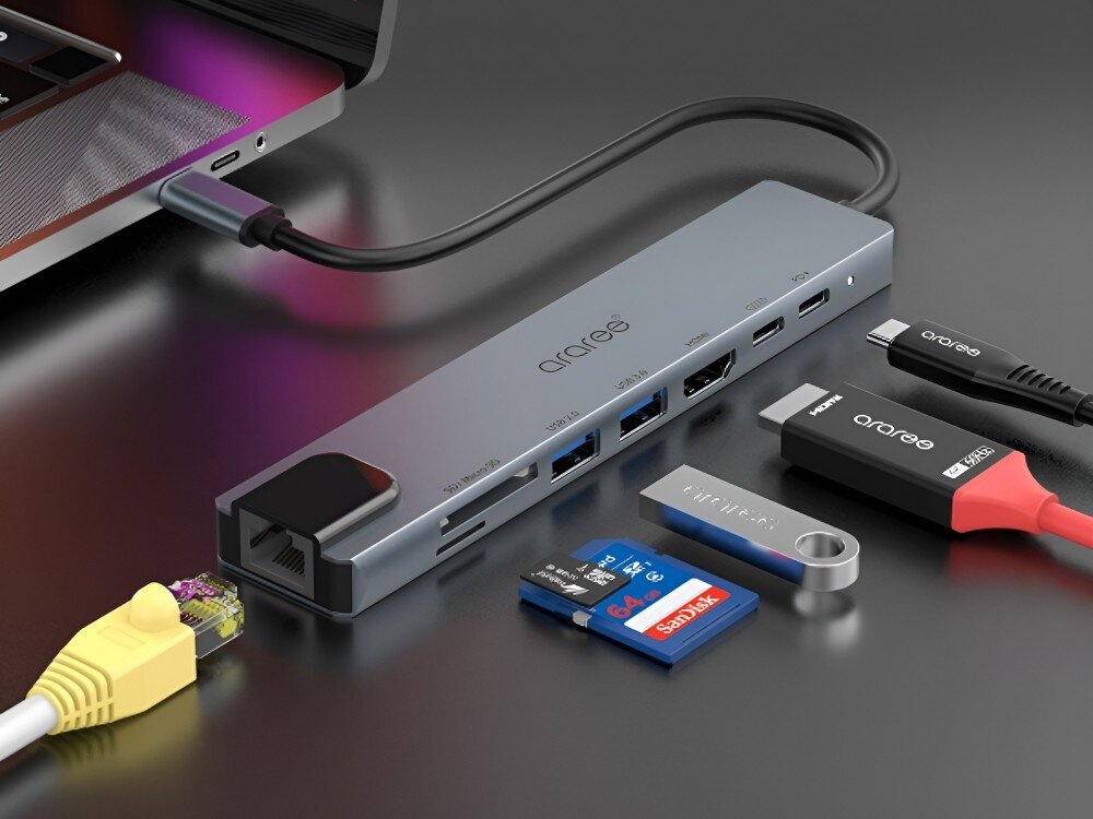 Hub ARAREE AM81 8w1 Hub USB-C podłączony do laptopa, otoczony kablami, pendrive’ami, kartami pamięci i adapterami. Na urządzeniu widoczne są różne typy portów, 
            hub adapter gadżet technologia komputer laptop