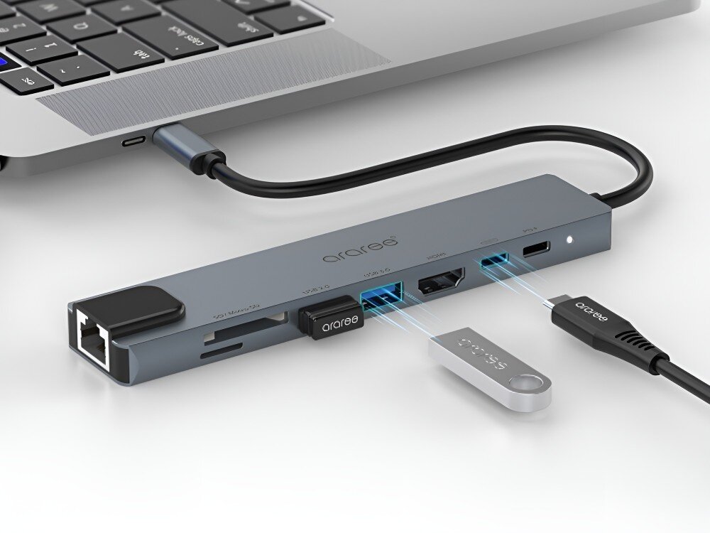 Hub ARAREE AM81 8w1 Hub USB-C podłączony do laptopa. Do portów wpinane są urządzenia, a obok leżą dodatkowe akcesoria, 
            hub hdmi usba usbc sd microsd rj45