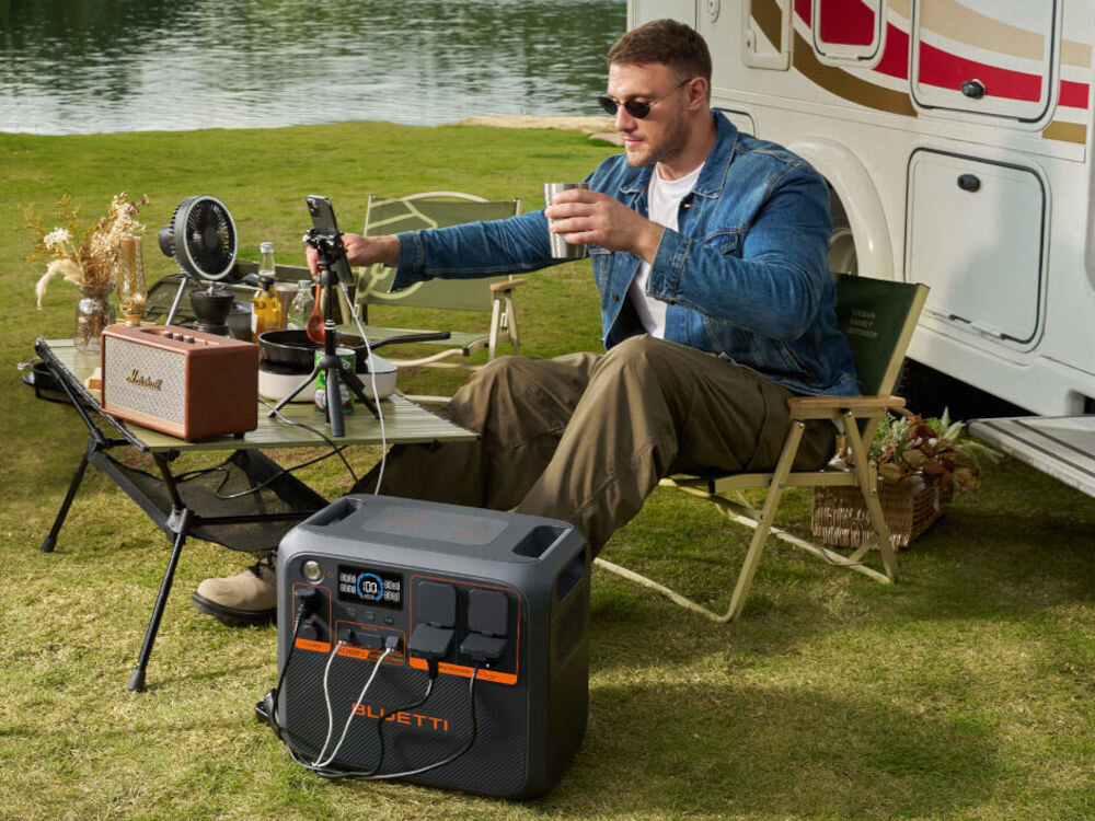 Stacja zasilania BLUETTI AC200PL 2304 Wh Bank energii, zasilanie, moc, prąd, energia, mężczyzna siedzi przy kamperze a obok stacja zasila jego sprzęt elektroniczny