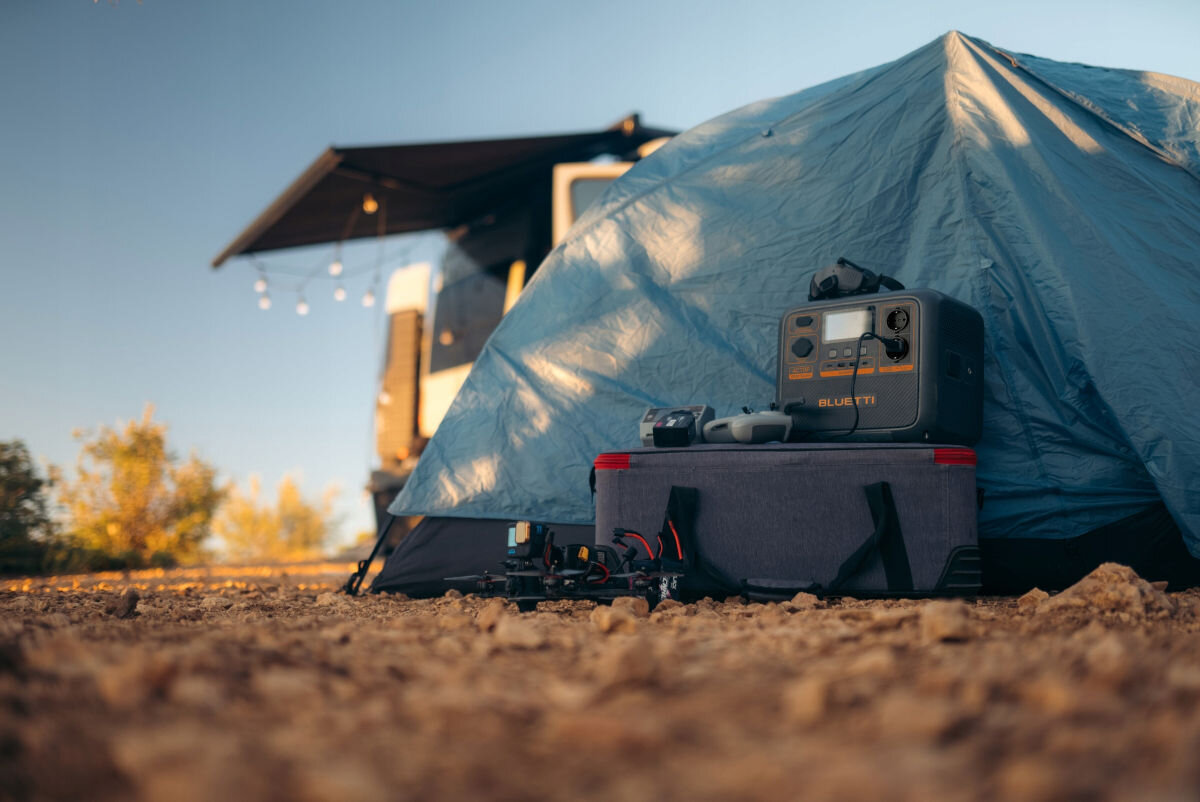 Stacja zasilania BLUETTI AC70P 864 Wh Bank energii, ładowanie, energia, zasilanie, mobilne, stacja stoi na skrzynki obok namiotu na dworze