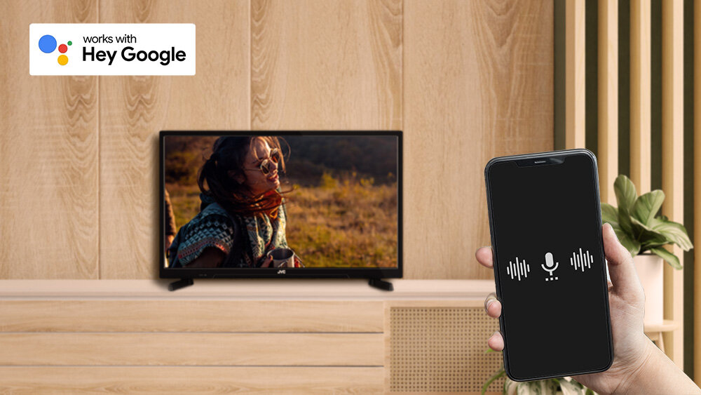 Telewizor JVC LT-24VAHM330 - Wygodna obsługa głosowa, dłoń trzymająca smartfon w ręku, telewizor stojący na komodzie