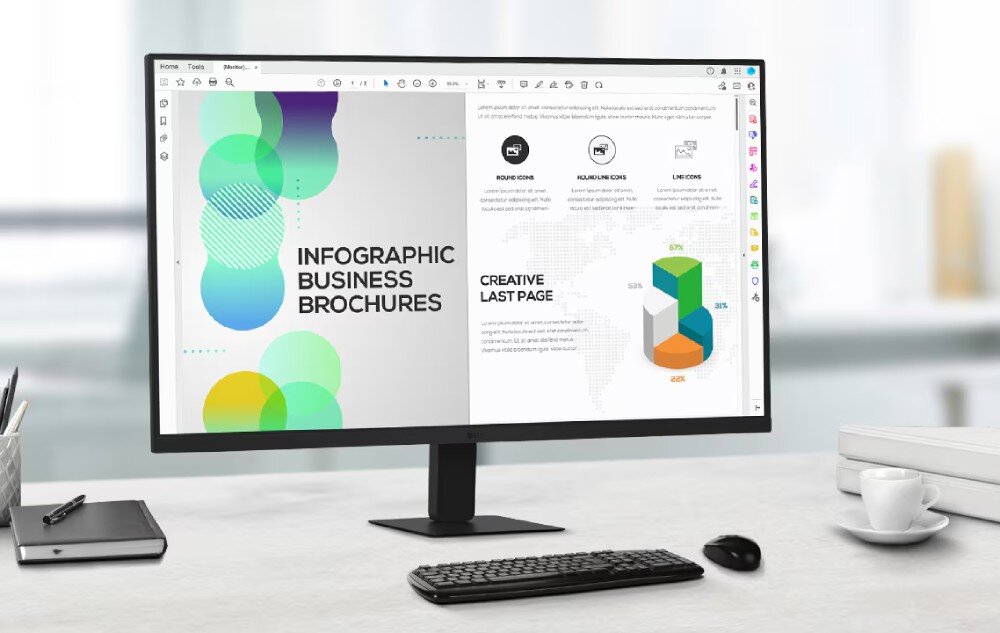 Monitor LG 27U631A-B Monitor na biurku, wyświetlający dokument z kolorową grafiką po lewej stronie i czarno-białą stroną z wykresem kołowym po prawej. Obok monitora klawiatura, myszka, notes i filiżanka na spodku, opis