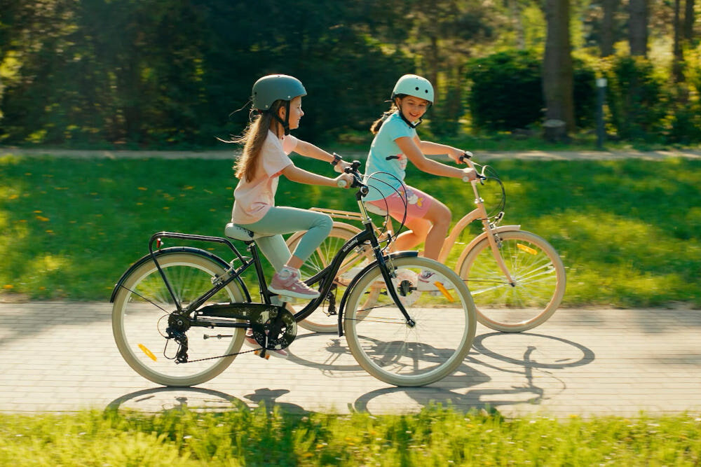 Rower młodzieżowy SUN BABY Flower Bike 24 cale dla dziewczynki Morelowy dwie dziewczynki jadą na rowerach po chodniku w tle trawa i drzewa odpowiednio wyselekcjonowane materiały stalowa 14,5-calowa rama dostosowana do najmłodszych geometria ponadprzeciętna odporność na uszkodzenia mechaniczne i działanie czynników zewnętrznych  wybór rozmiaru ramy Twój wzrost mierzony w zrelaksowanej pozycji typ roweru