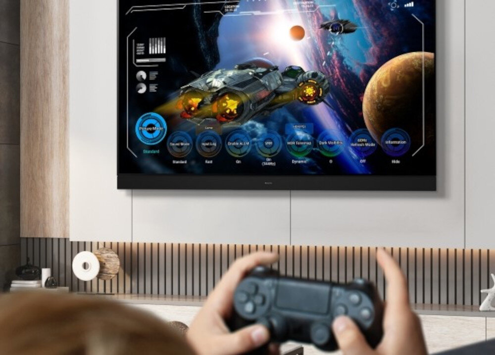 Telewizor PANASONIC TV77Z93AEG Game Control Board gry konfiguracja MY APP, telewizor zawieszony na ścianie z włączoną grą wideo, osoba trzymająca kontroler w ręku