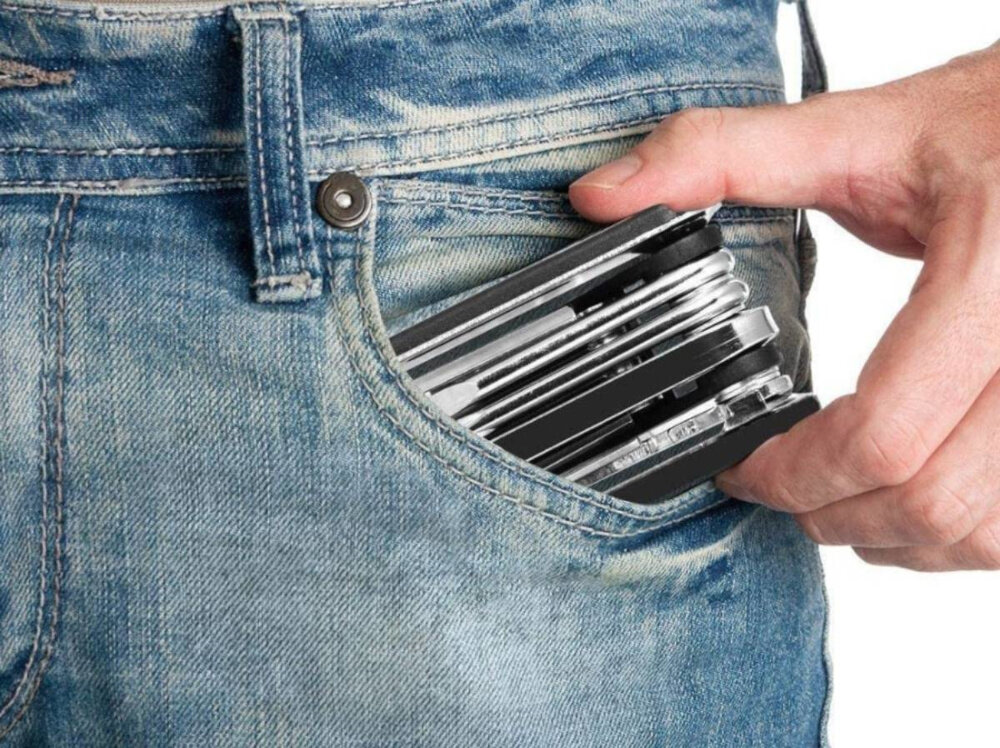 Klucz rowerowy EXTRALINK 14300 białe tło osoba w jeansach wkłada klucz do kieszeni multitool niezbędnik rowerzysty do naprawy rowerów