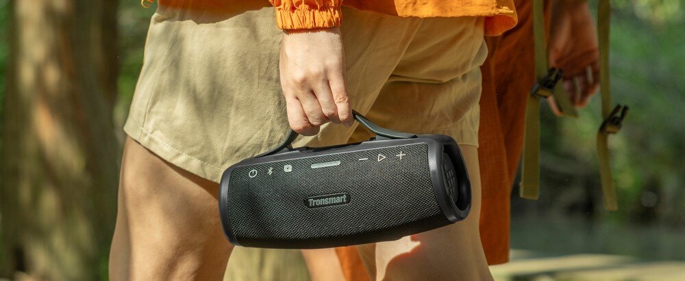 Głośnik TRONSMART Mirtune S100 przenośny z uchwytem podróżny, osoba trzymająca głośnik za uchwyt