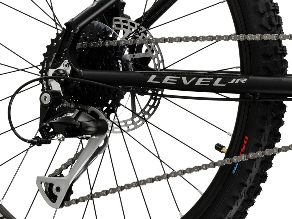 Rower młodzieżowy KROSS Level Jr 3.0 24 cale dla chłopca Czarno-niebiesko-srebrny zbliżenie na tylną przerzutkę 9-biegowy system przerzutek marki SHIMANO płynna zmiana przełożeń dopasowanie jazdy do różnych warunków terenu tylna przerzutka SHIMANO Tourney precyzyjna praca mechanizmu użytkownik może łatwo dostosować tempo i wysiłek do swoich potrzeb