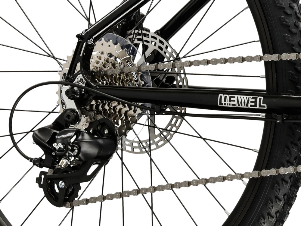 Zbliżenie na mechanizm tylnej przerzutki roweru z widocznym napisem \'LEVEL\' na ramie. Widać również tarczę hamulcową i łańcuch na zębatkach.