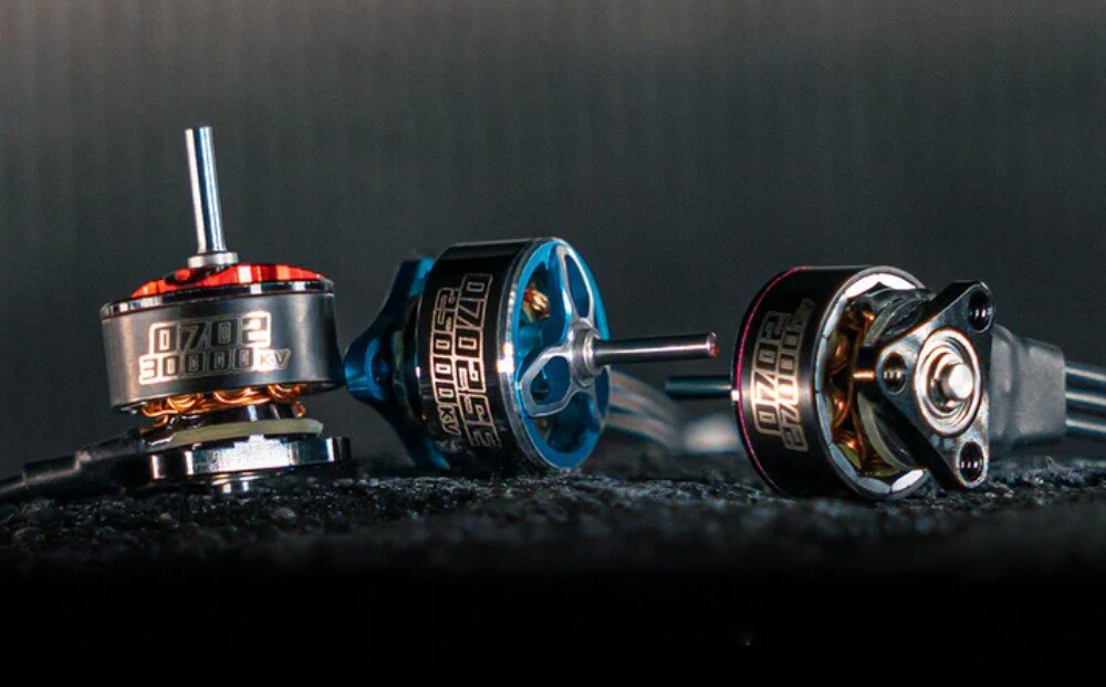 Silnik BETAFPV 0702SE 25000KV (4 szt.) Trzy silniki modelarskie na ciemnej powierzchni, z których lewy stoi pionowo i ma oznaczenie '30000KV', środkowy z niebieskimi elementami i napisem '25000KV' leży na boku, a prawy leży poziomo ukazując czarną obudowę i spód
