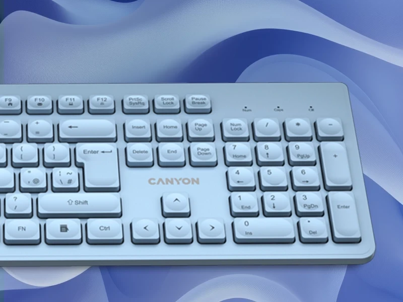 Na obrazie widoczna jest niebieska klawiatura z logo \'CANYON\' na środku. Tło ma abstrakcyjny wzór w odcieniach niebieskiego.