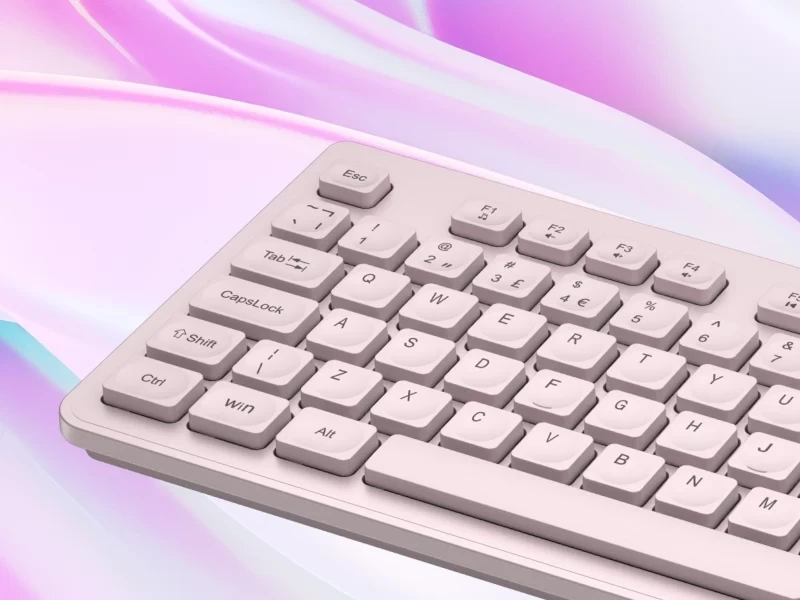 Beżowa klawiatura z widocznymi klawiszami, takimi jak Esc, F1-F3, Tab, CapsLock, Shift, Ctrl, Win, Alt oraz literami QWERTY. Tło jest w pastelowych odcieniach różu i fioletu.
