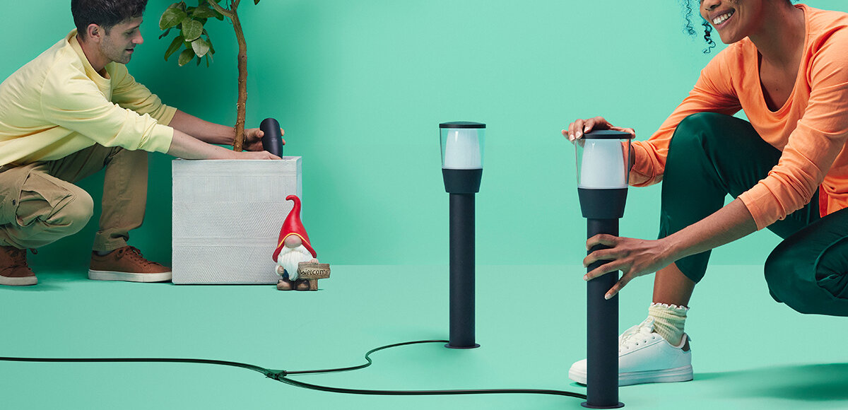 Lampa zewnętrzna WIZ Bollard Low 929003265101, Droga w blasku ogrodowego LED, Osoby ustawiają lampy w pomieszczeniu, demonstrują ustawianie